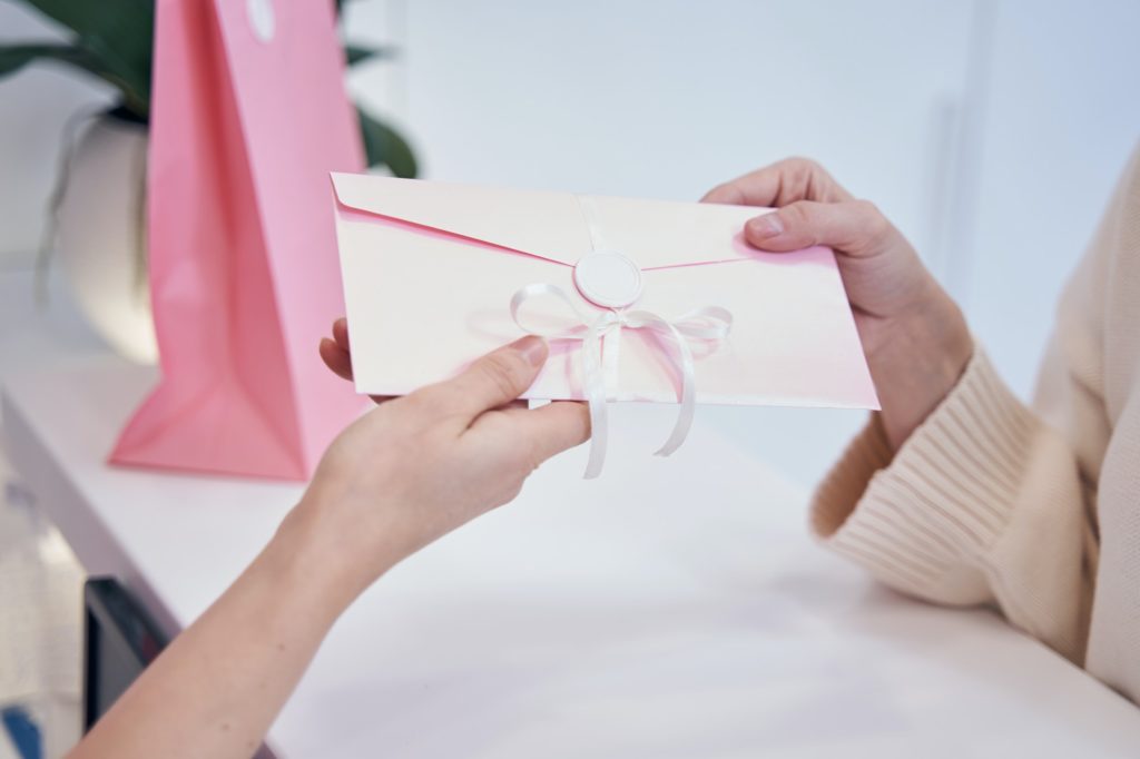 Aesthetic clinic employee presenting discount voucher to client